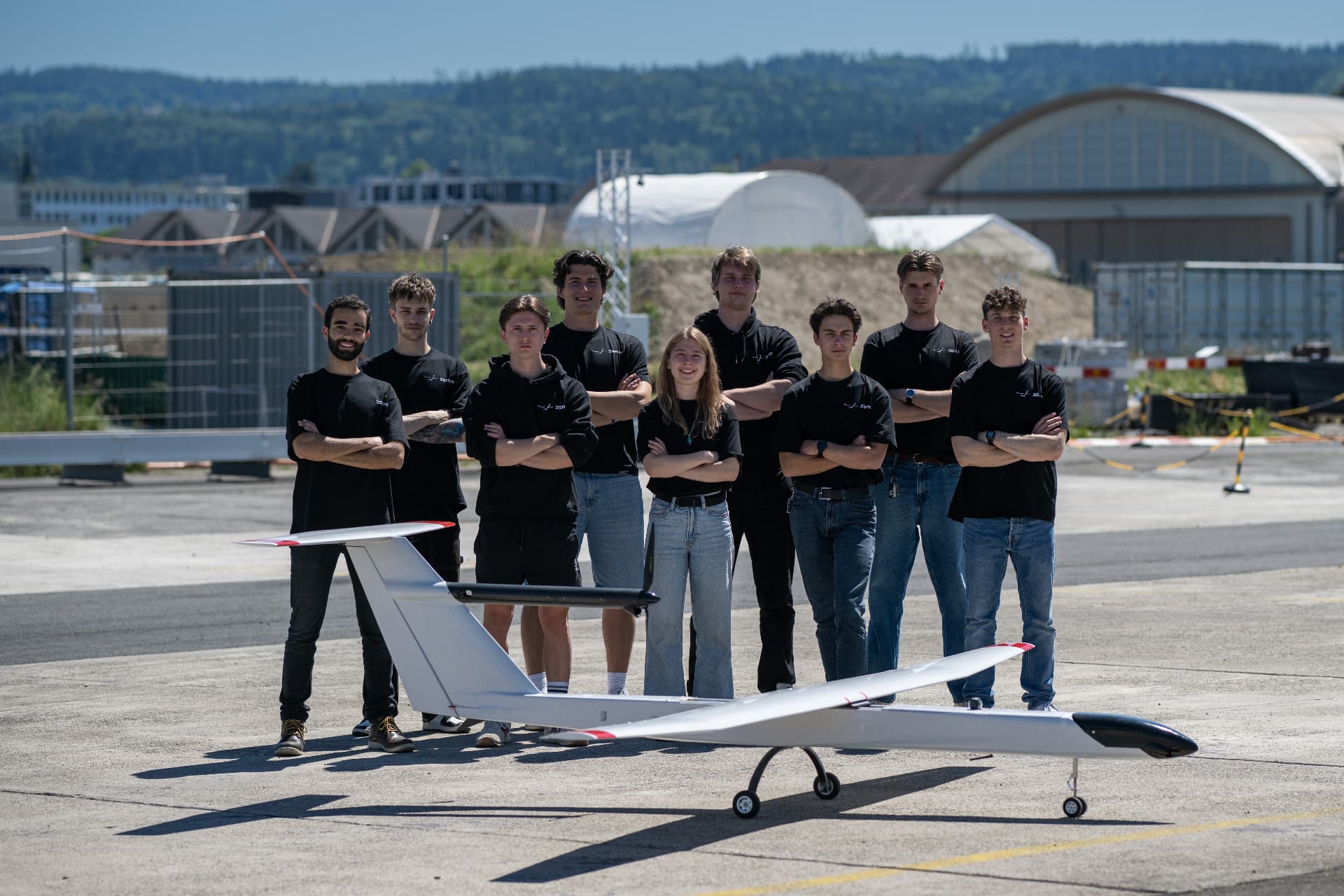 Zephyr team standing behind their fixed-wing aircraft